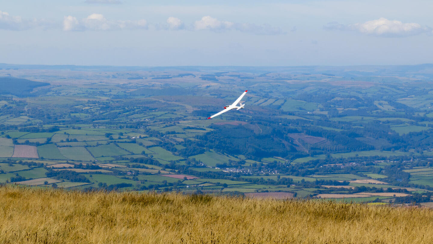 Ein Segelflugzeug fliegt über die Felder der ländlichen Umgebung.