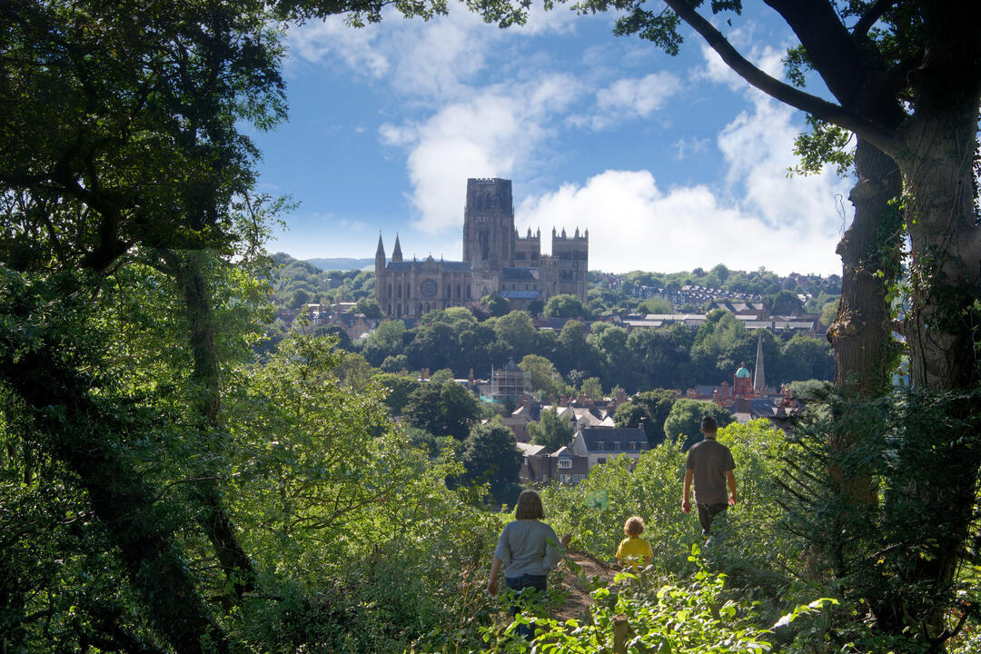 Family walking on a hill top looking down on to Durham Cathedral