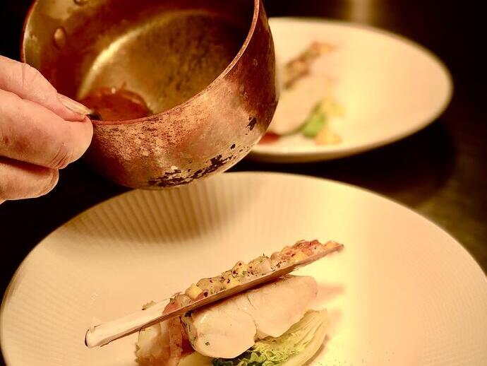 Gros plan sur une personne versant de la sauce sur un plat