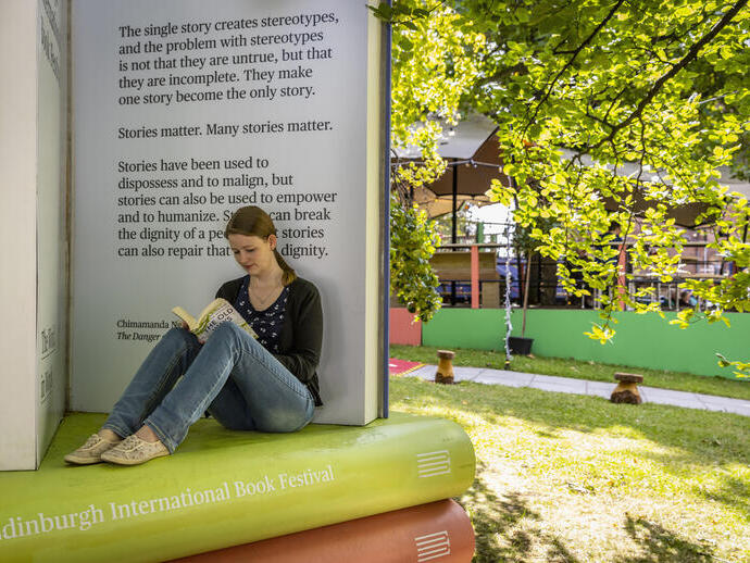 Frau, die bei einem Buchfestival sitzend liest