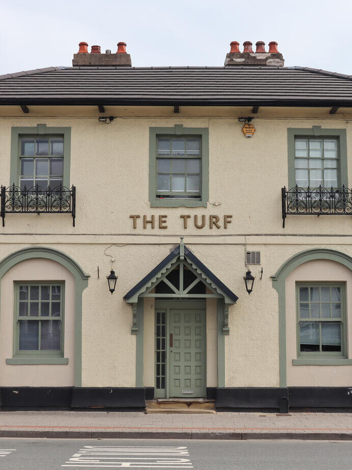 Entrance to a British pub with a sign that reads 'The Turf'.