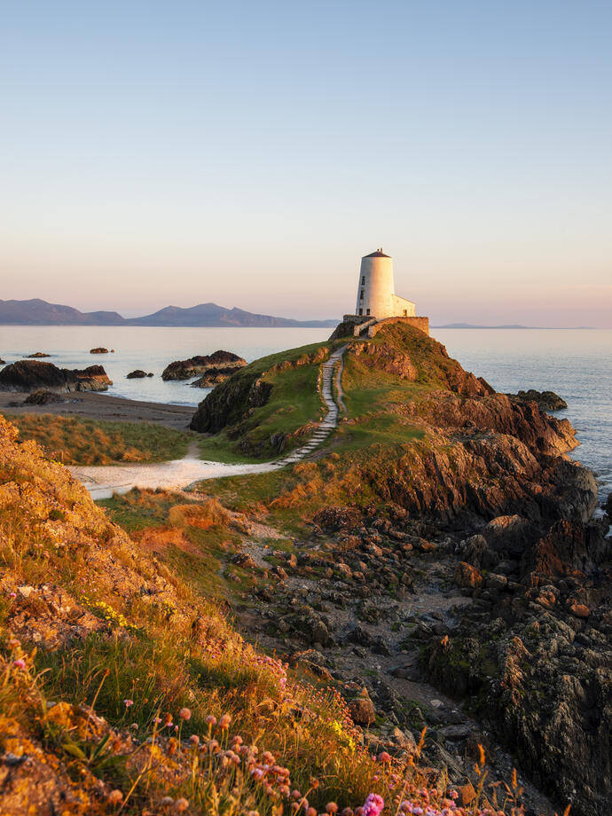 A path leading to a lighthouse on a prominent rocky outcrop by the sea