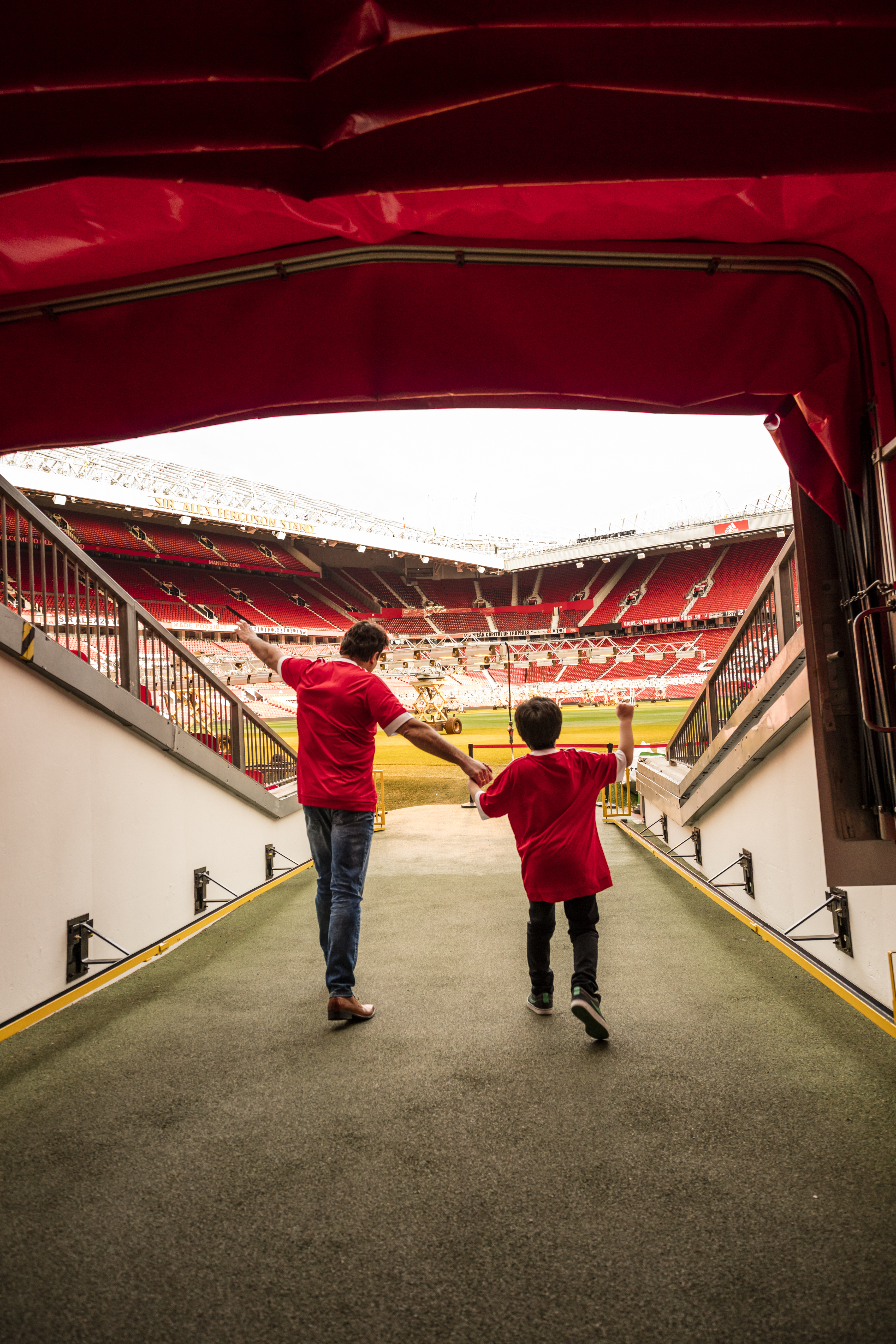 A man and boy in stadium tunnel looking out to pitch