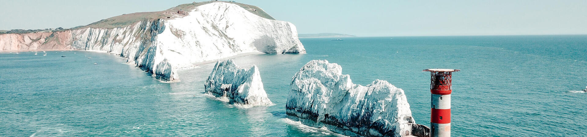 Tall chalk formations in a row running from the cliffs of the mainland to a lighthouse