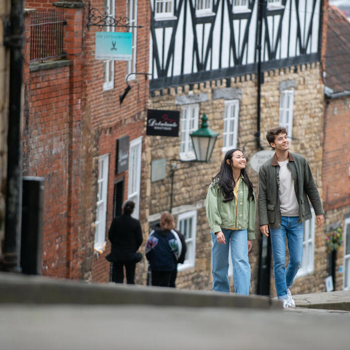 Eine Frau und ein Mann gehen einen steilen Hügel in einer historischen Stadt hinauf