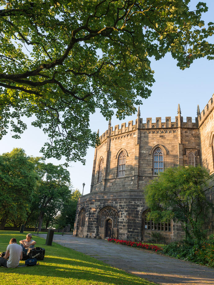 Vista esterna del castello di Lancaster con visitatori seduti sul prato in primo piano