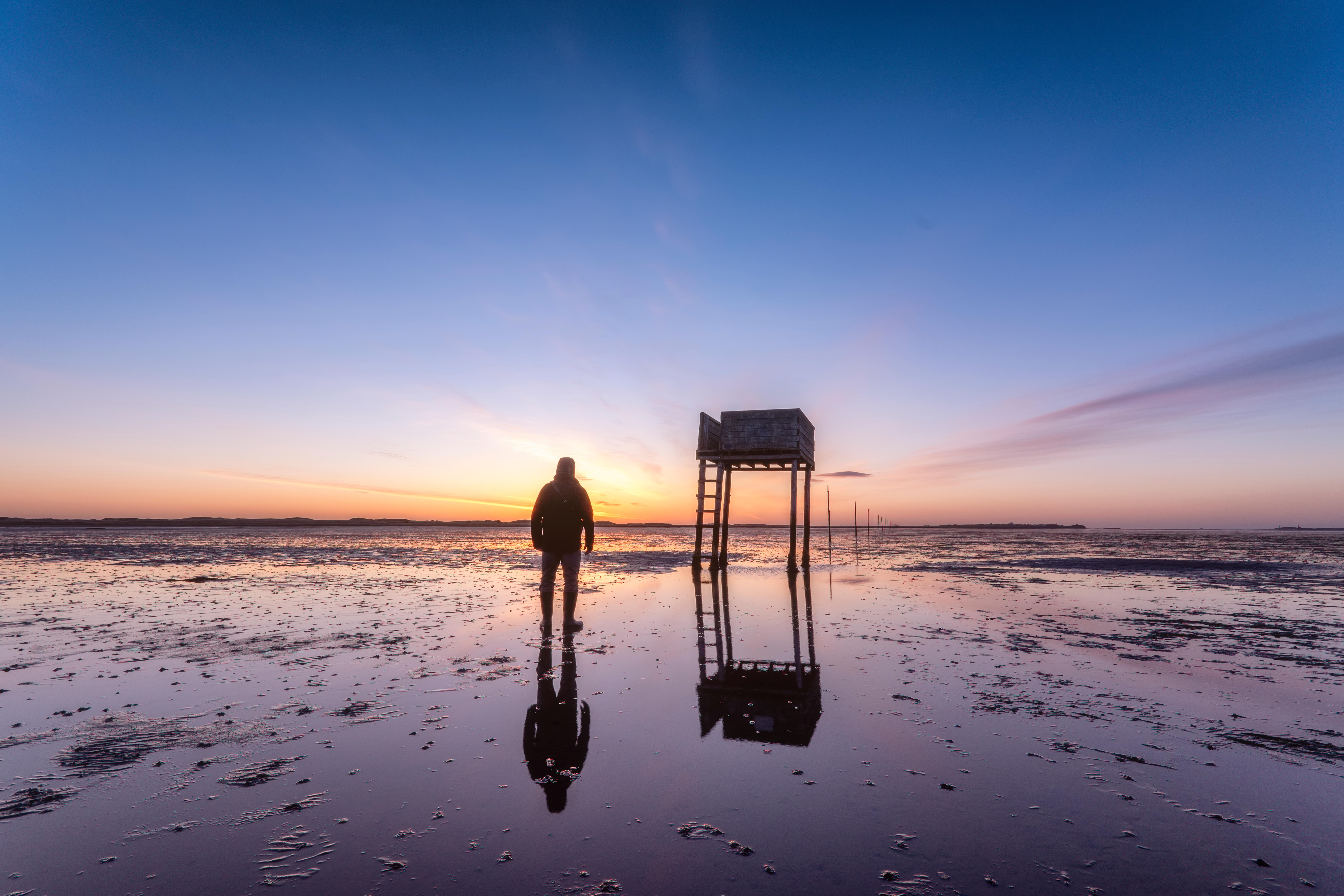 Posts marking the pilgrims' way crossing to Lindisfarne with emergency refuge at sunrise