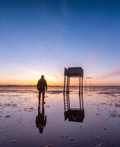 Pali che segnano il percorso dei pellegrini che attraversano Lindisfarne con rifugio di emergenza all'alba