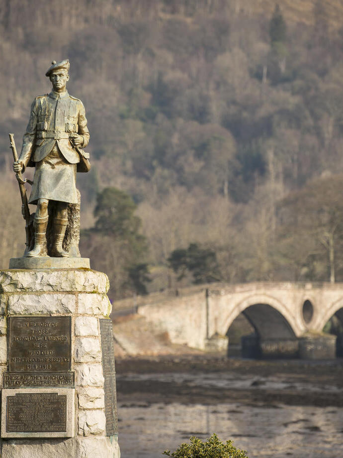 Une statue commémorative de guerre devant un pont en arc.