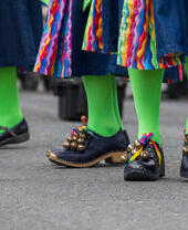People in green tights and black shoes dancing at a folk festival.