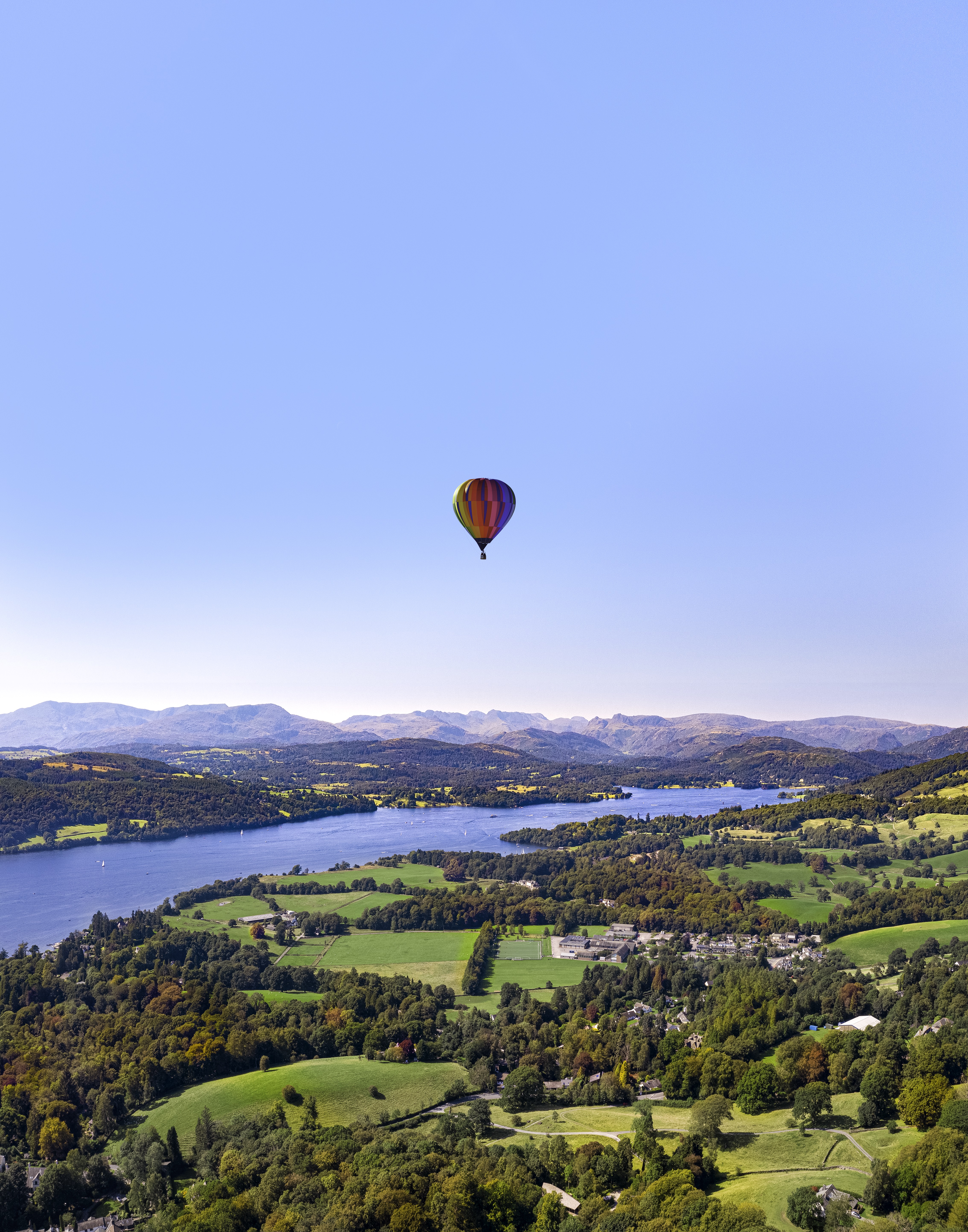 Hot air balloon in clear skies over green countryside fields