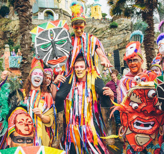Gruppe von Darstellern in bunten Kostümen mit bemalten Gesichtern