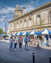 Group of friends walking in a town street past market stalls