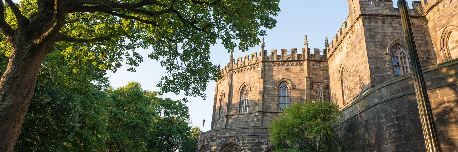 Außenansicht des Lancaster Castle mit Besuchern, die auf dem Rasen im Vordergrund sitzen