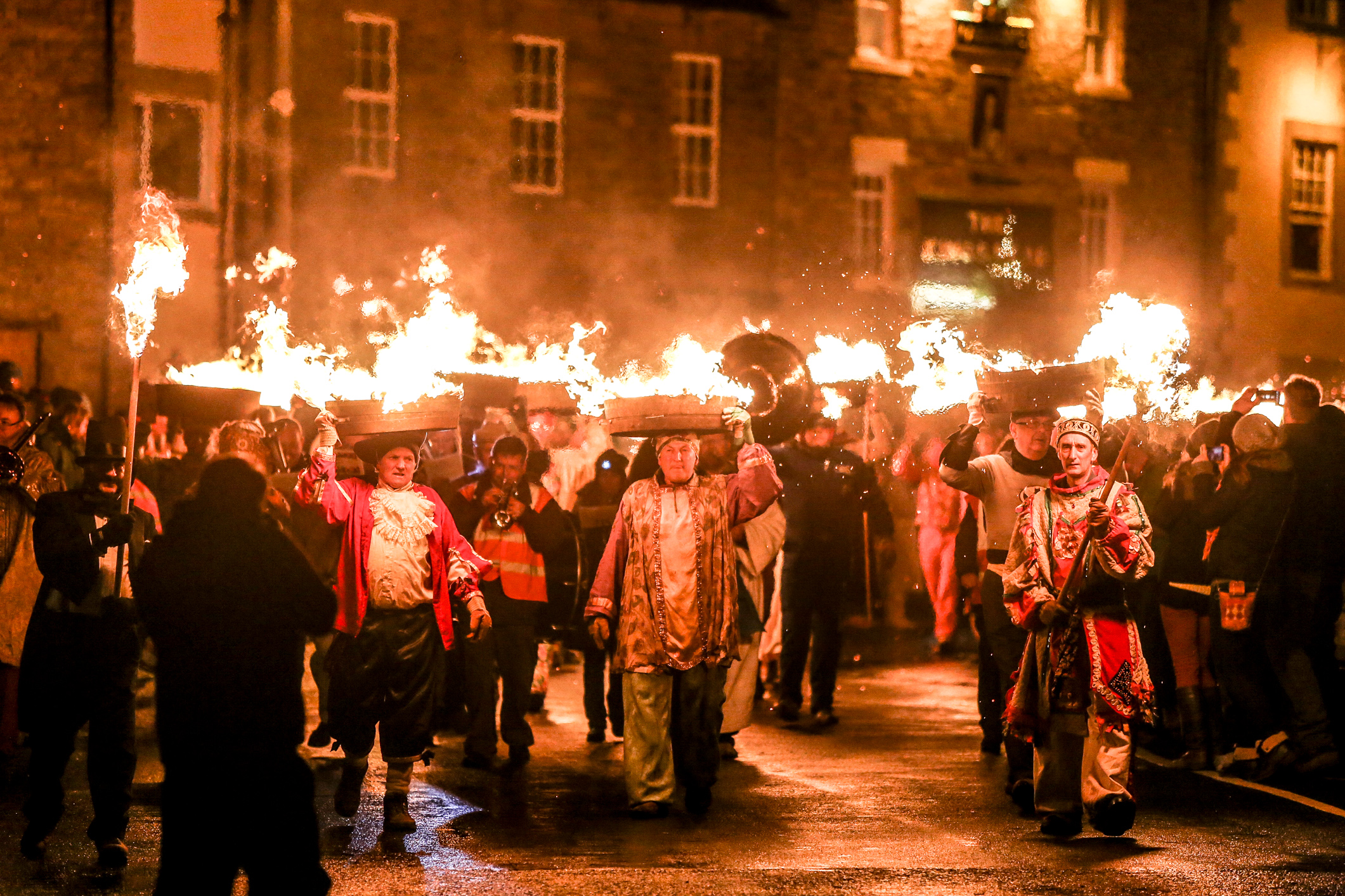 A procession of people in costumes with flaming containers on their heads - Allendale Tar Bar’l