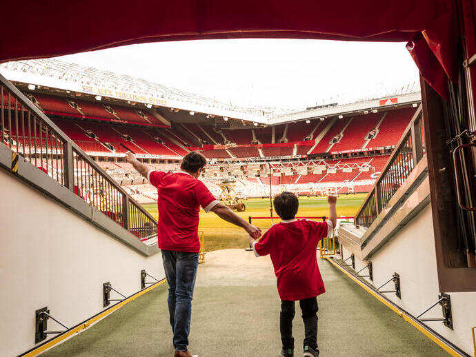 A man and boy in stadium tunnel looking out to pitch