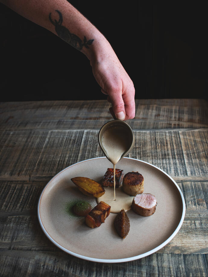 Chef adding dressing to a plate of food