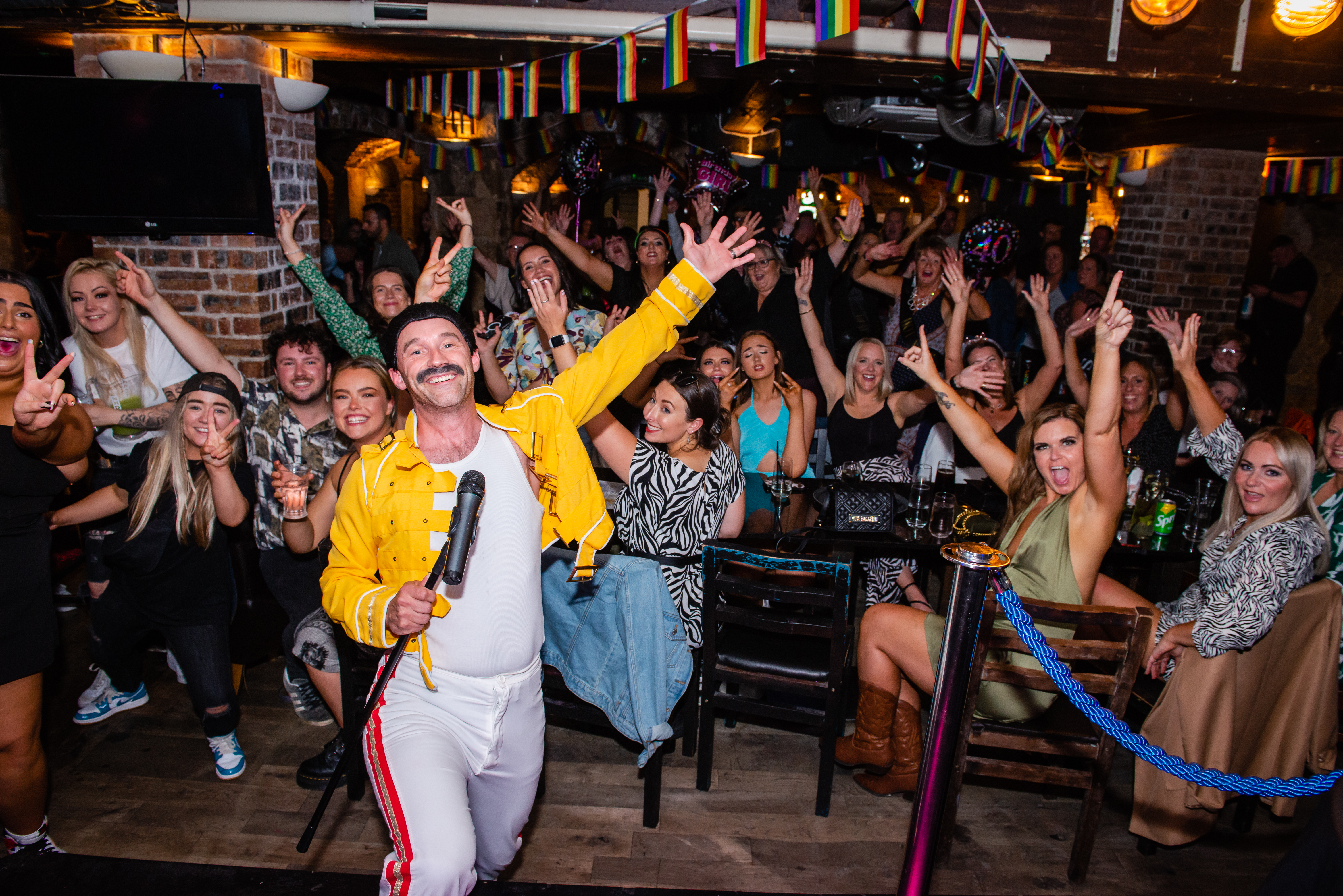 Freddy Mercury impersonator on stage in front of a crowd at Katie's Bar and Kitchen in Glasgow, Scotland