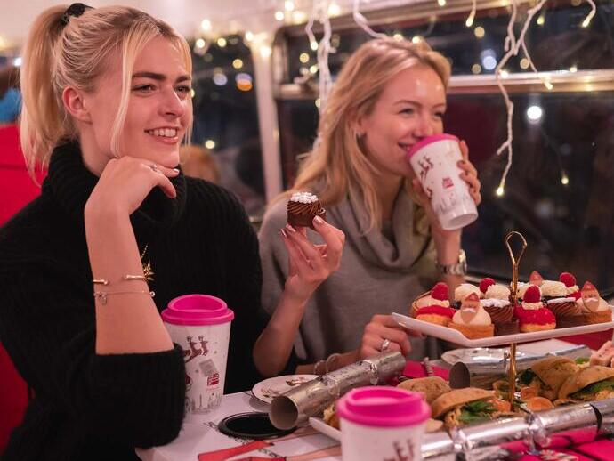 Two women sitting at a table and eating a Christmas Afternoon Tea in a bus experience