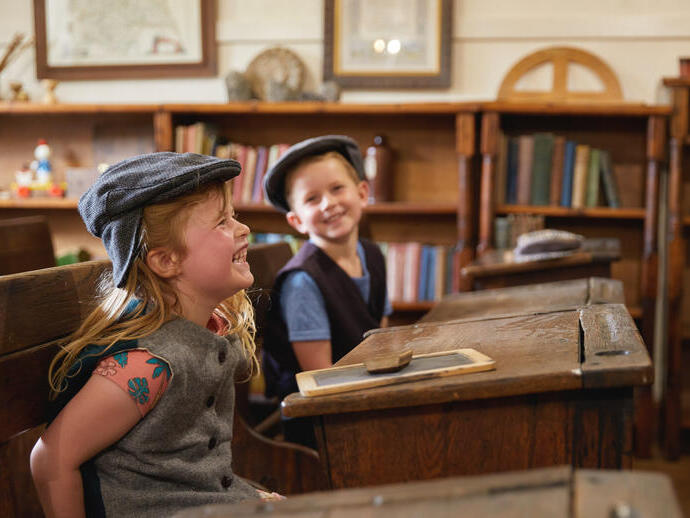 Two children stiiling at school desks - Ryedale Folk Museum