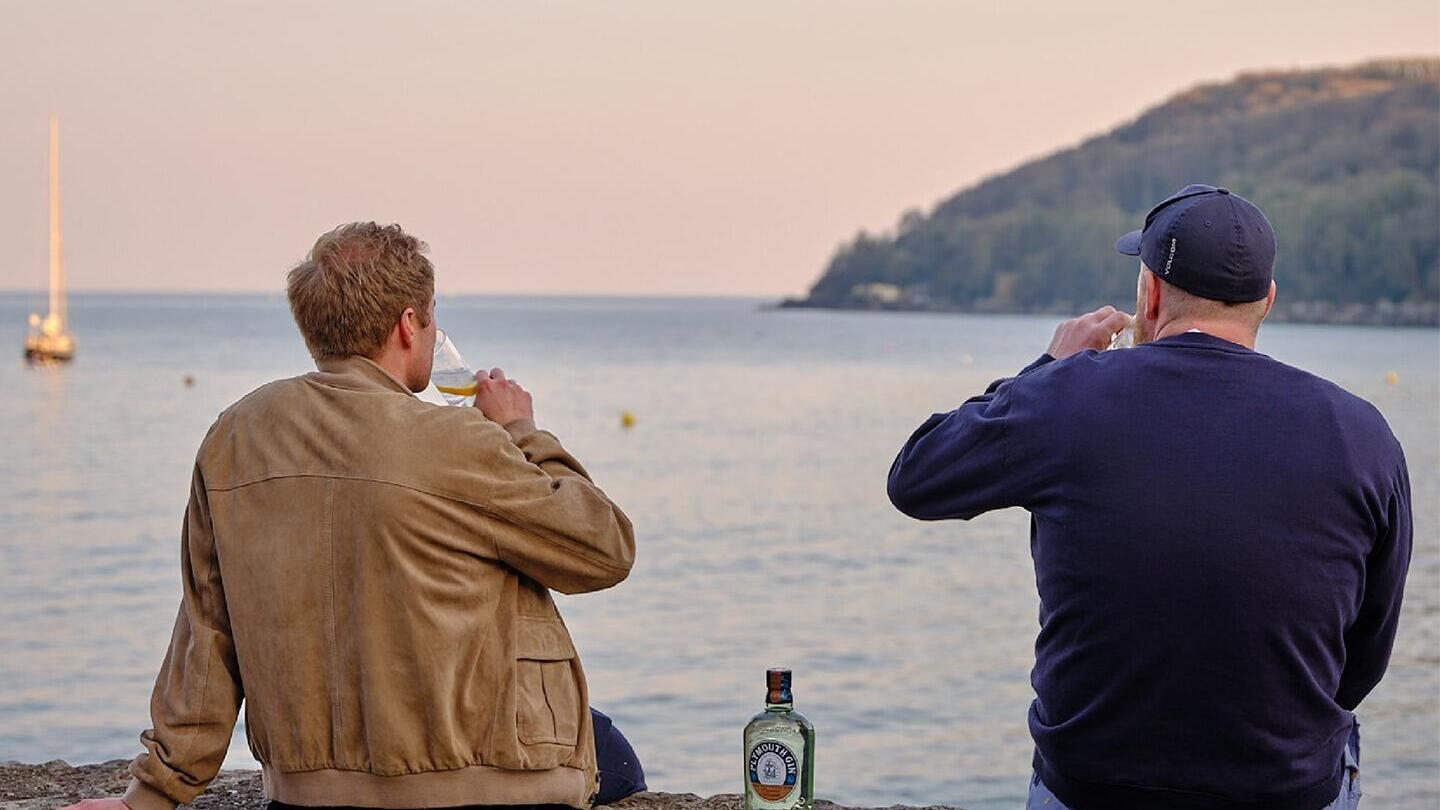Two men drinking gin looking out to sea