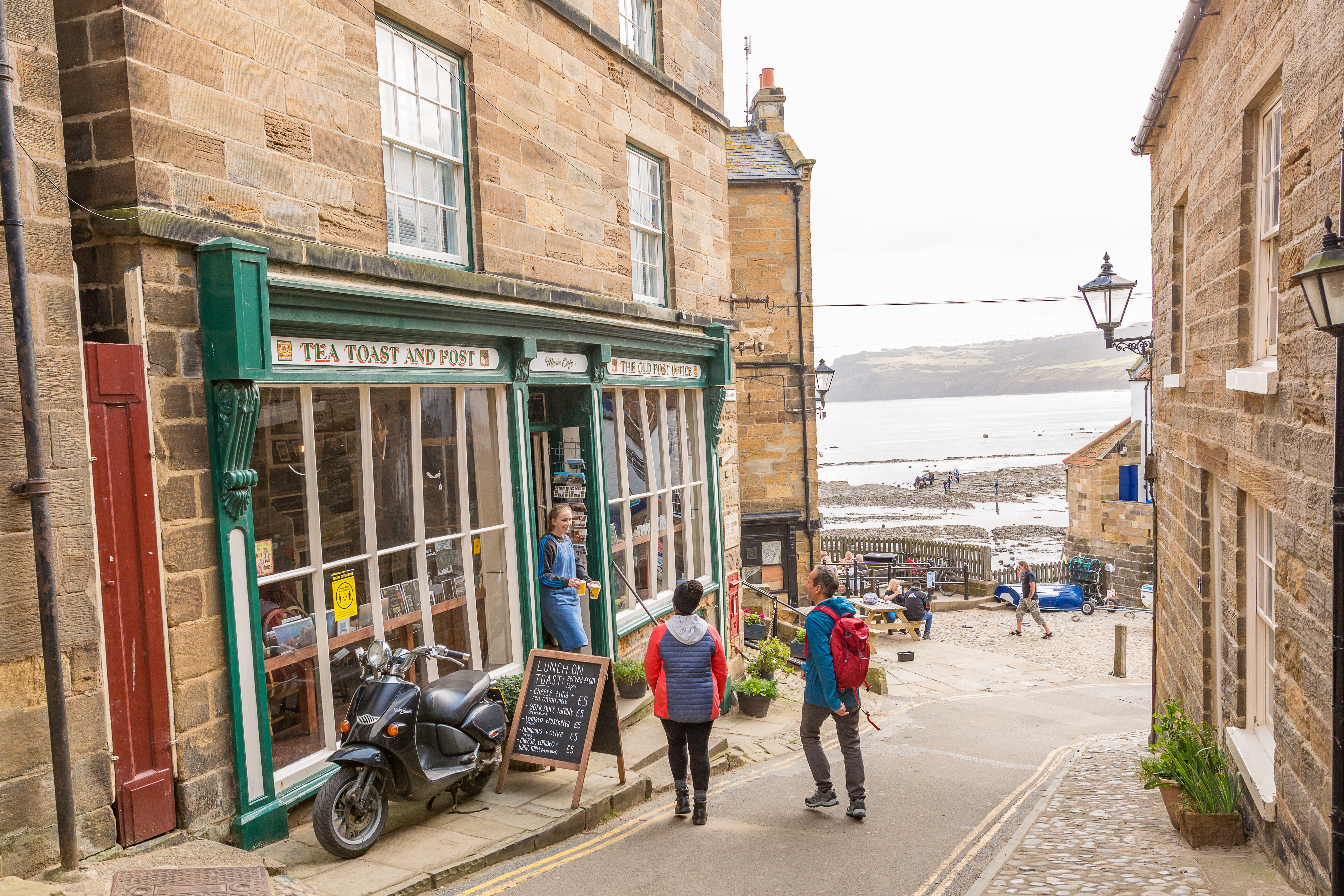 Couple walking down a narrow street with the sea in the distance