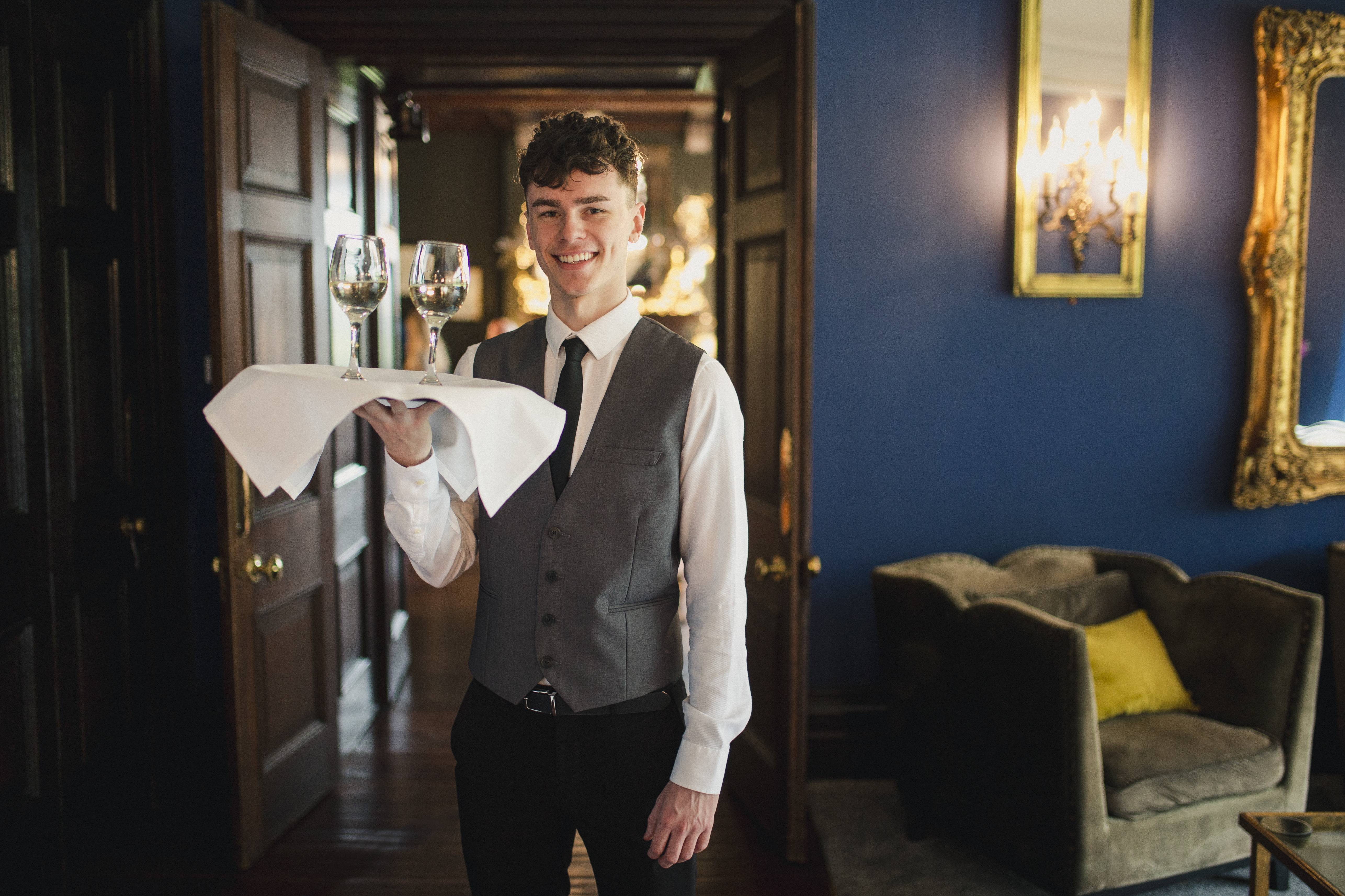 Member of staff holding a tray with two glasses of wine in a restaurant