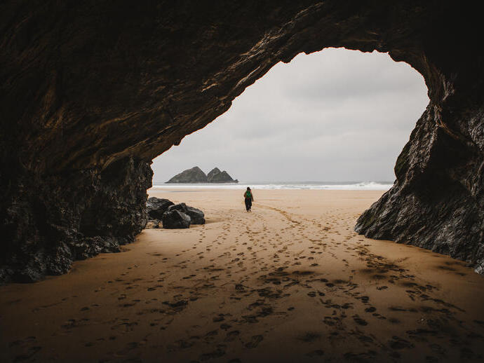 A woman walks through a cave on a beach