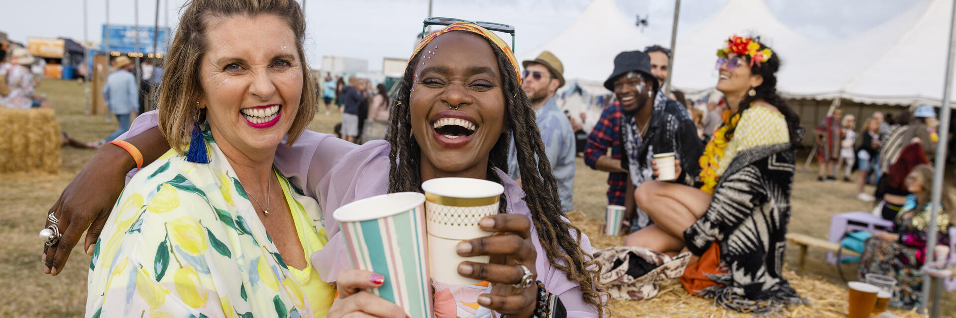 Zwei Frauen, die sich mit Freunden auf einem Festival amüsieren.