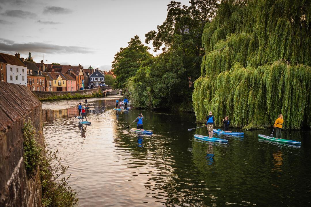 A group of people paddleboarding on the River Wensum