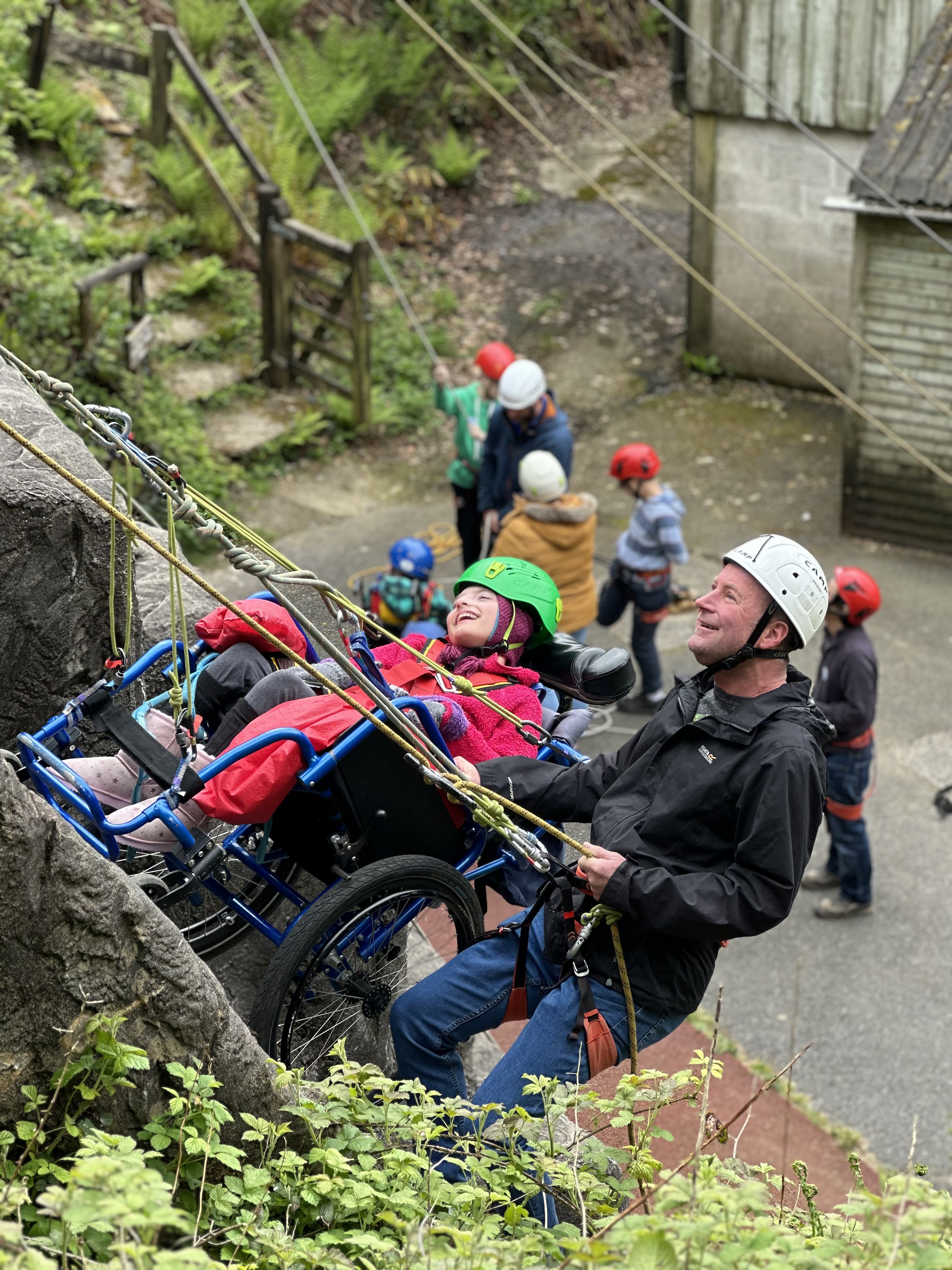 A girl in a wheelchair and a man abseil at an accessible outdoor activity centre