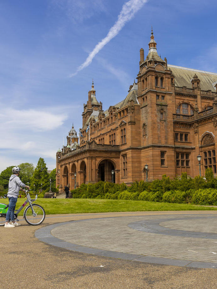 A cyclist parked out the front of an ornate Art Gallery and Museum.