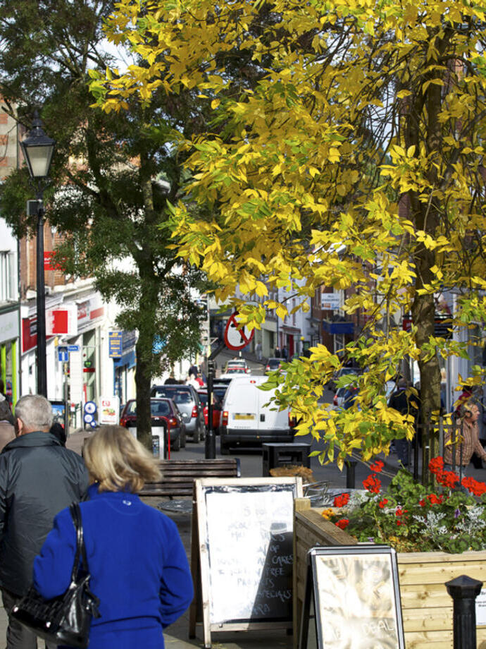 Persone che camminano lungo una strada commerciale collinare in una piccola città.