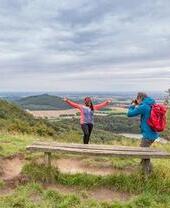 Frau posiert vor ländlicher Kulisse, während ein Mann Fotos macht