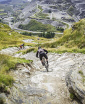 People mountain biking down a steep hill.