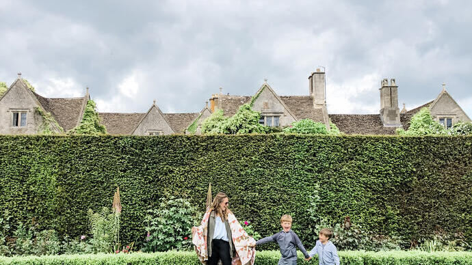 Mother and sons standing in garden in front of a tall hedge