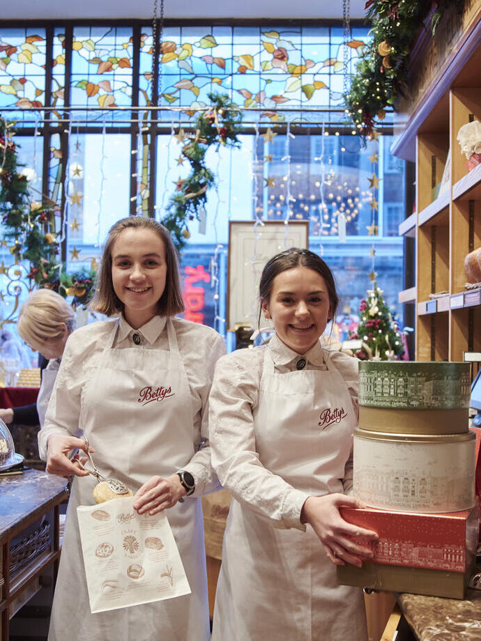 Two waitresses stood behind counter of tea shop