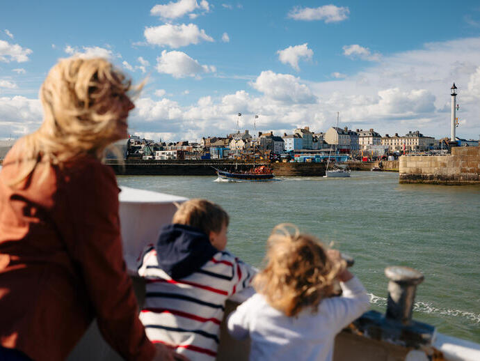 A family lean on a boat looking out to a harbour