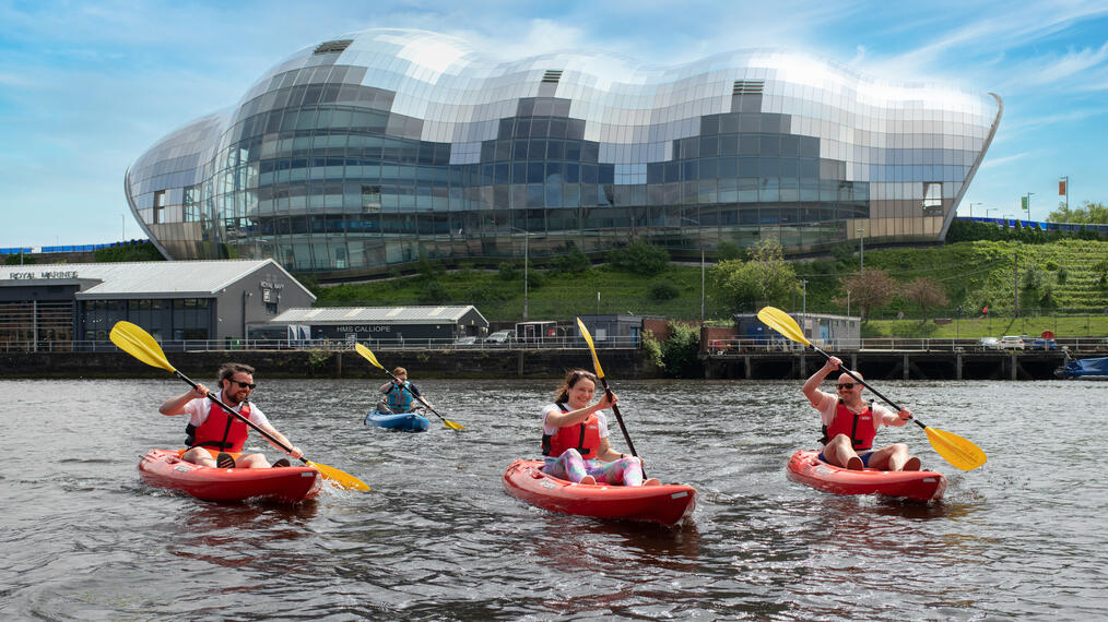 A group of people kayaking in front of an iconic building