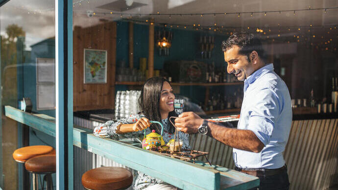 Woman being served a drink by a member of staff in a cafe.