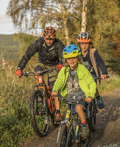 Adult and two children cycling on a path through the countryside