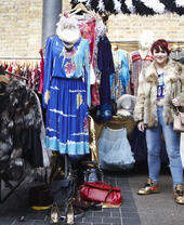 Woman standing by a vintage clothing market stall.