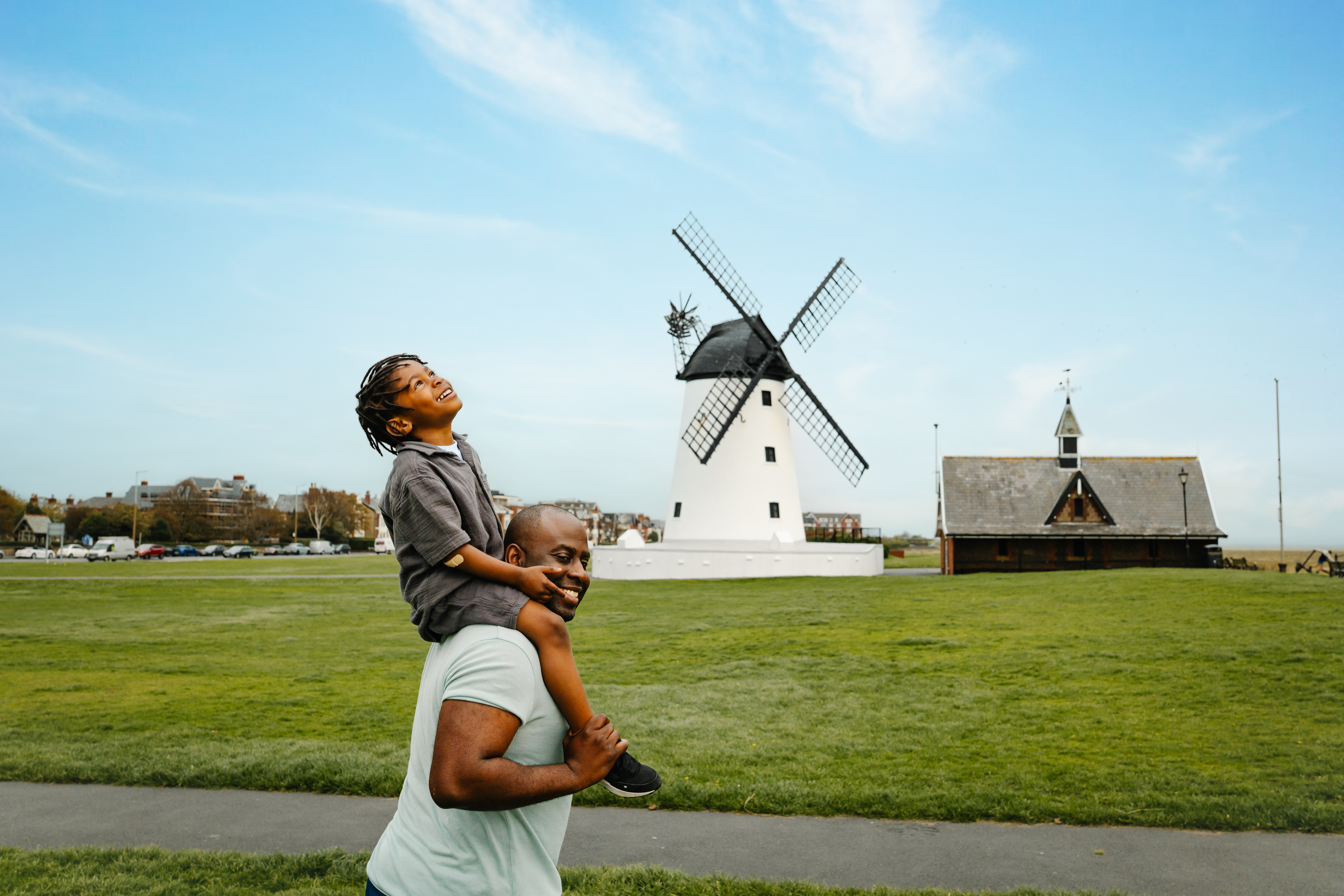 A father and son have fun in a field in front of a windmill