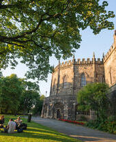 Außenansicht des Lancaster Castle mit Besuchern, die auf dem Rasen im Vordergrund sitzen