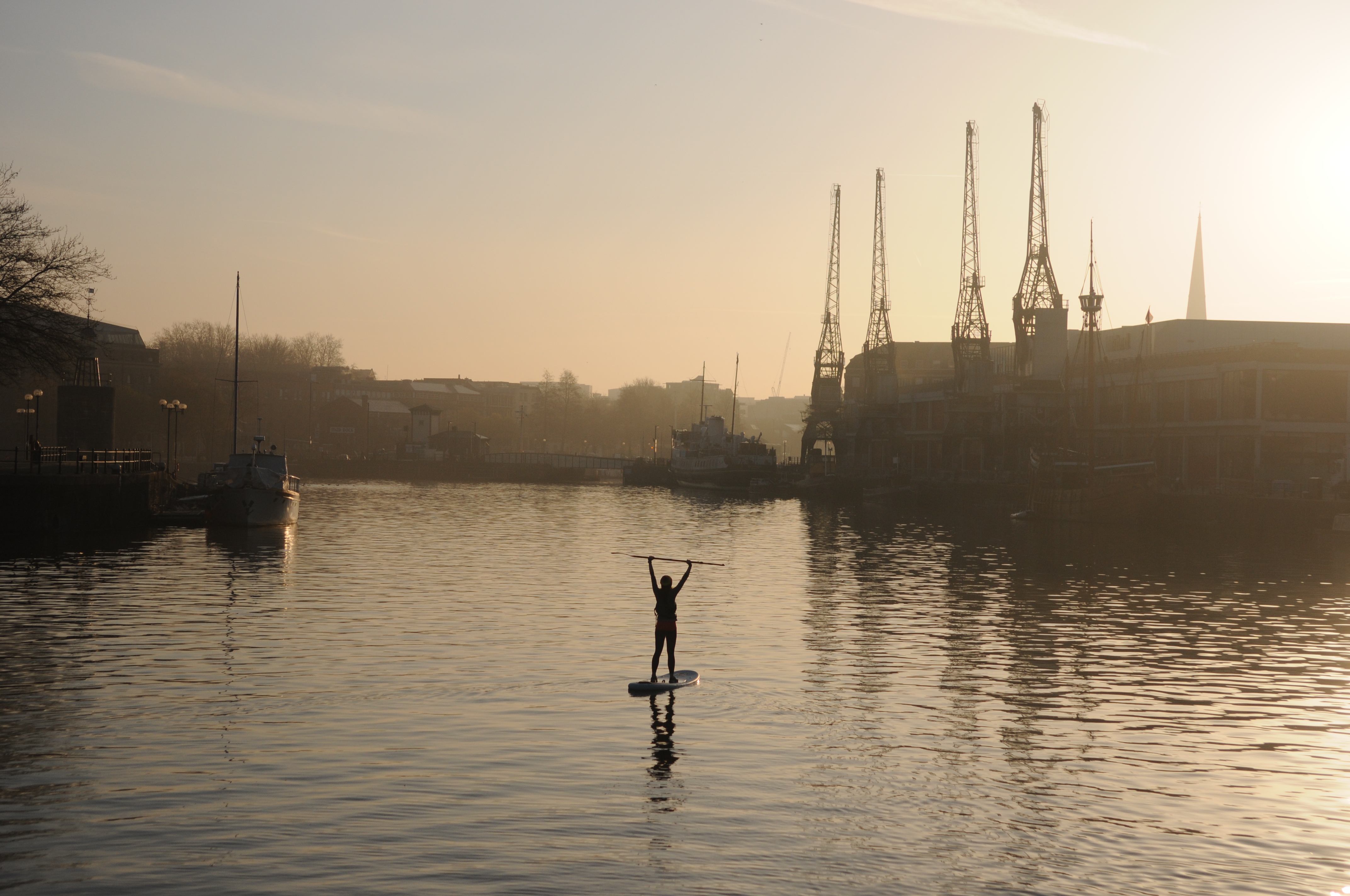 A person paddleboarding in the middle of Bristol's harbourside