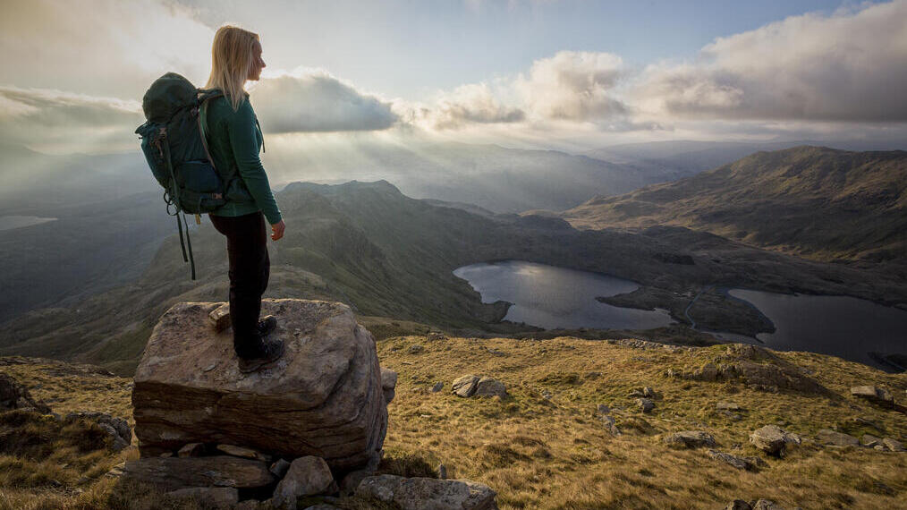A young woman standing on rocks at a lookout point.