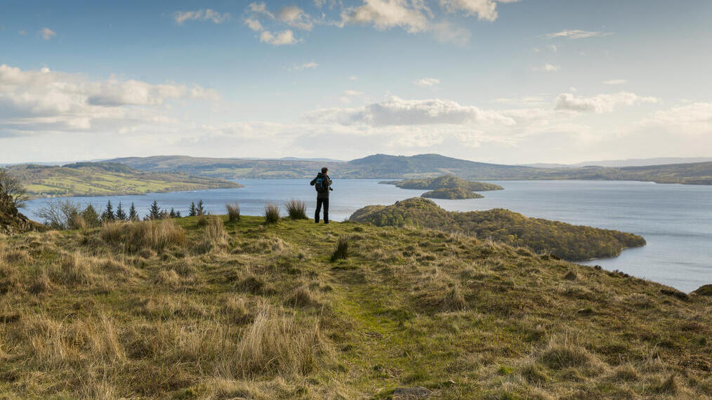 Caminante contemplando las vistas del lago Lomond desde Conic Hill, parte de la ruta West Highland Way