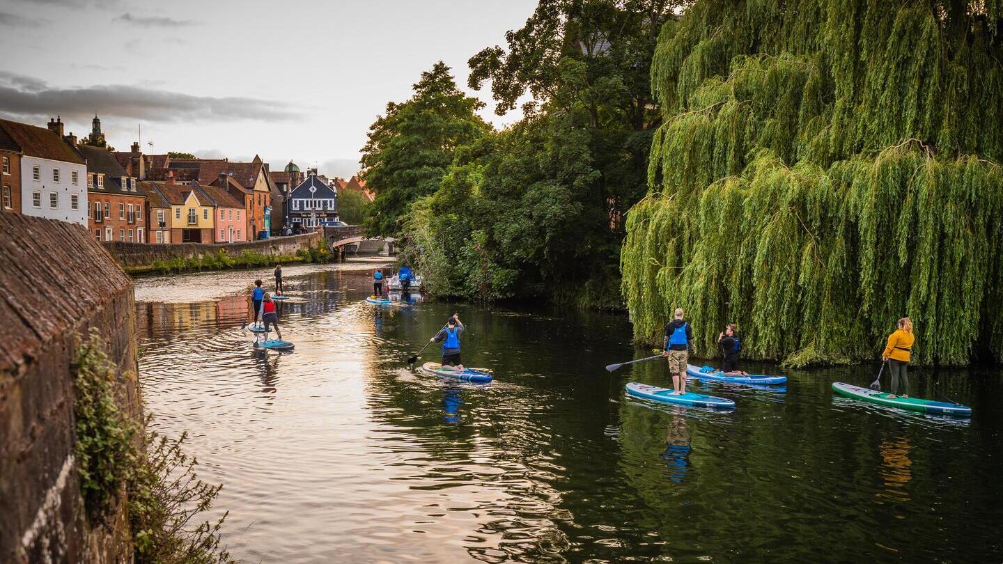Un gruppo di persone che fa paddleboarding sul fiume Wensum