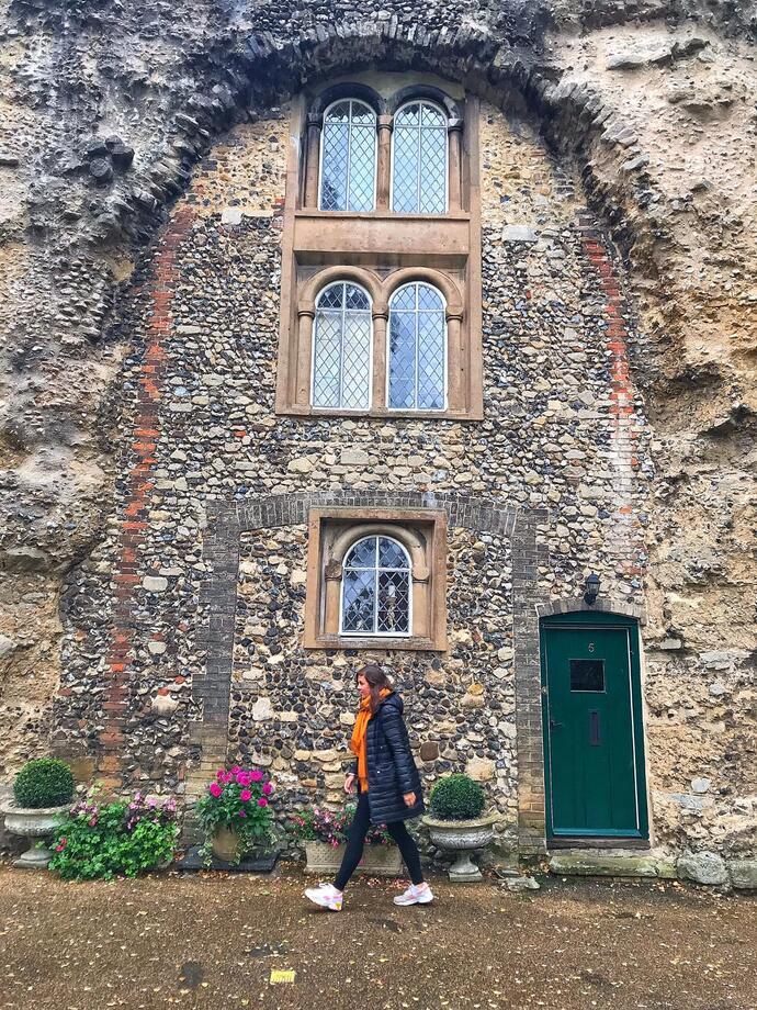 Woman walking in front of a stone cottage