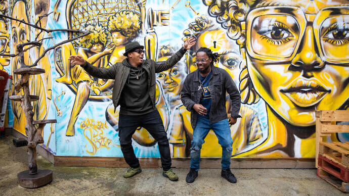 Two men standing in front of street art, dancing